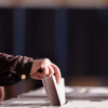 Hand of a person casting a vote into the ballot box during elections, from Roibu, Shutterstock